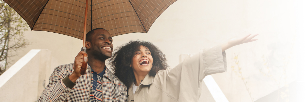 Couple standing under umbrella smiling towards the sky